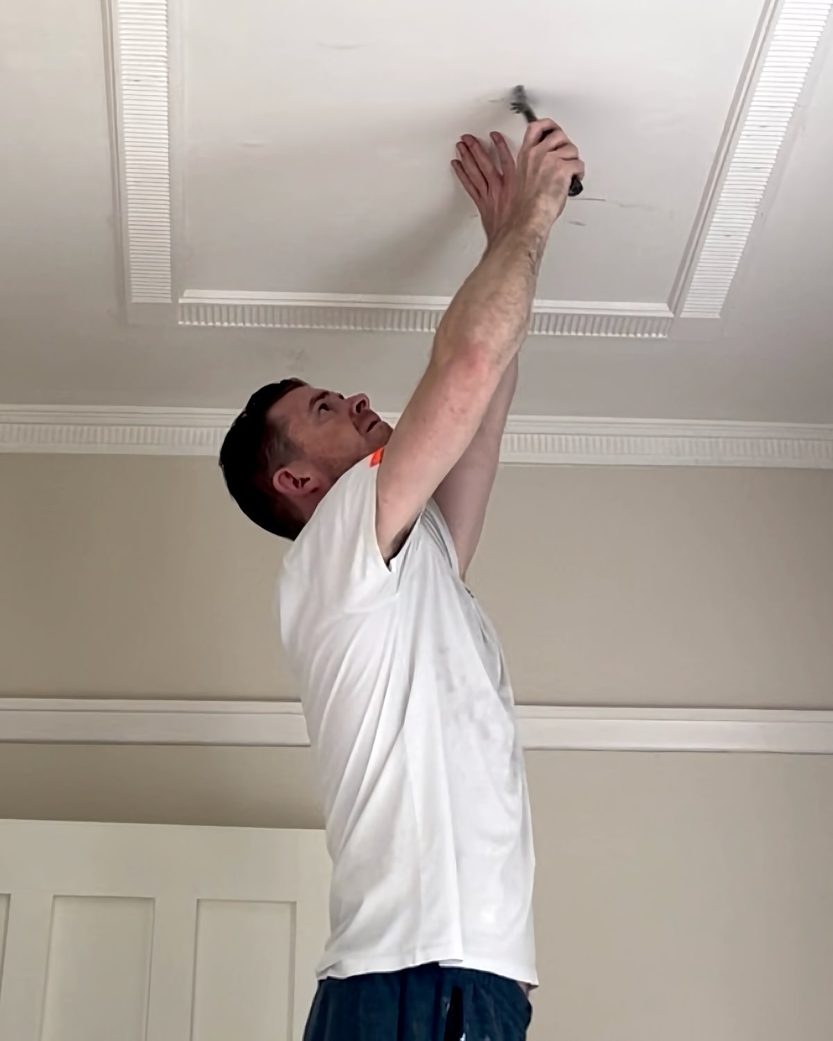 Andrew preparing to paint a ceiling with peeling paint