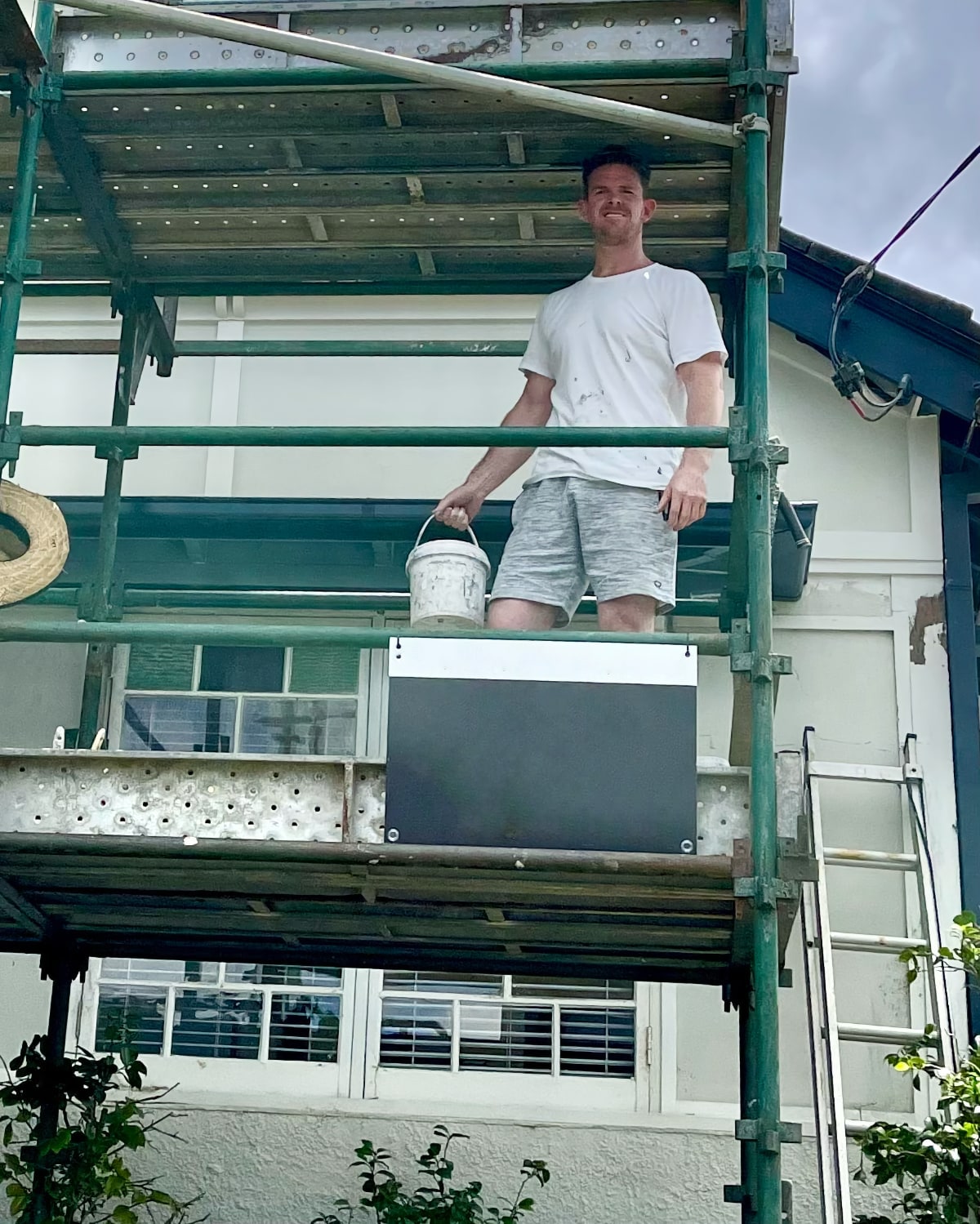 Andrew on a scaffolding working on a big exterior wall painting project