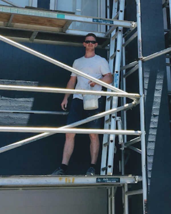 Andrew on a scaffolding working on a big home rennovation painting project